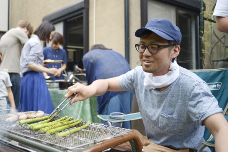 出店のおにーさん風にアスパラを焼くスタッフ・カナザワ